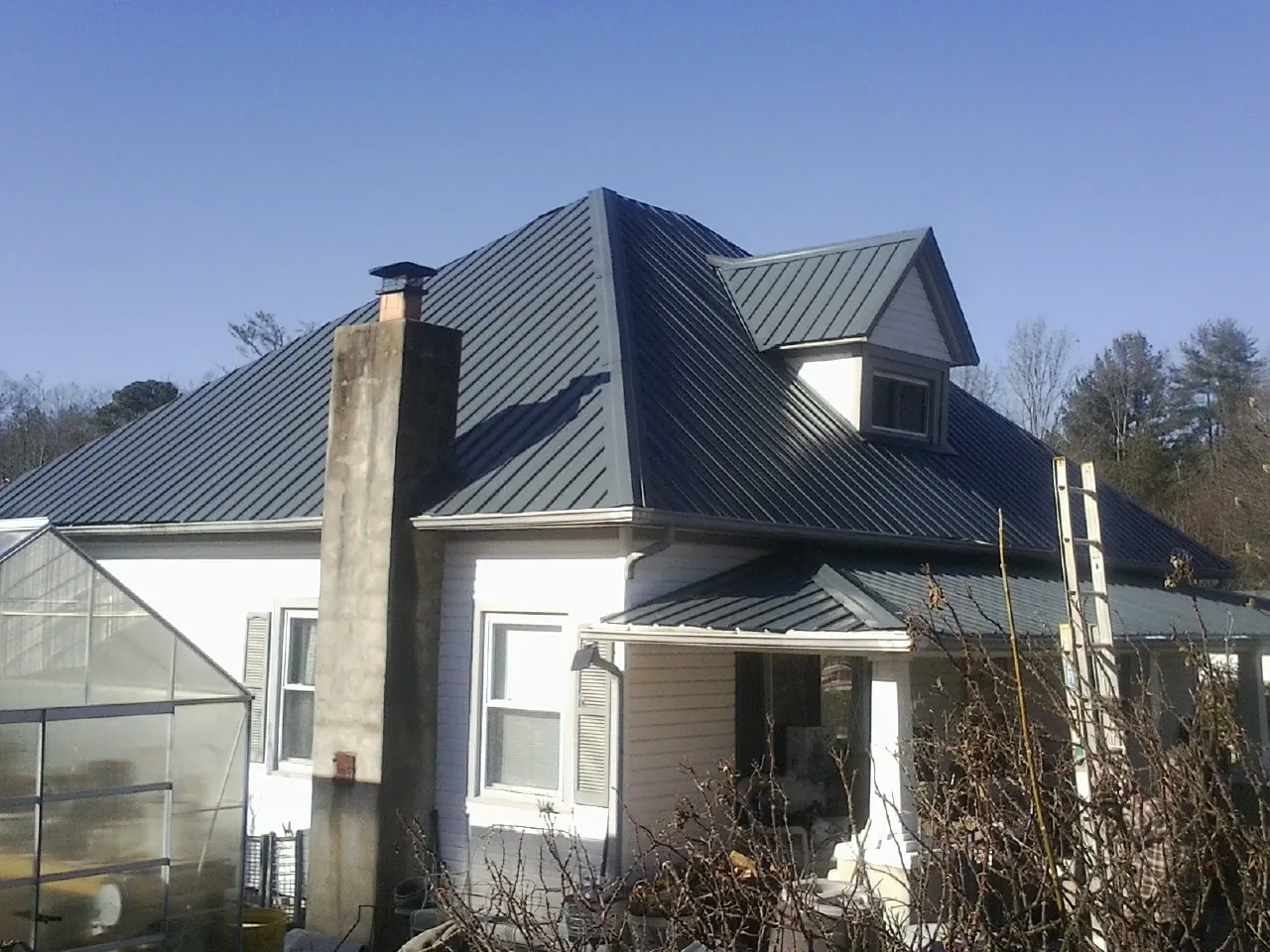 Dark blue standing seam metal roof on a white farmhouse with dormer — Slate & Tile Roof Repair by Roofing Brothers in Esmont