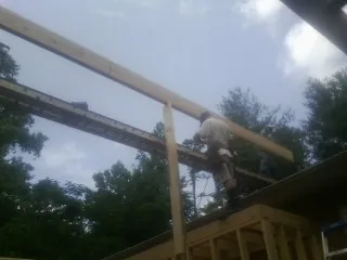 Carpenter setting a ridge beam over a new addition frame — Ice Dam Removal by Roofing Brothers in Esmont