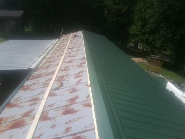 Old rusted panels beside newly installed green metal roofing — Wind Damage Roof Repair by Roofing Brothers in Esmont