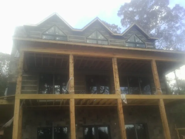 Dormers and porch framing on a large log home under construction — Roof Coating work by our crew in Esmont