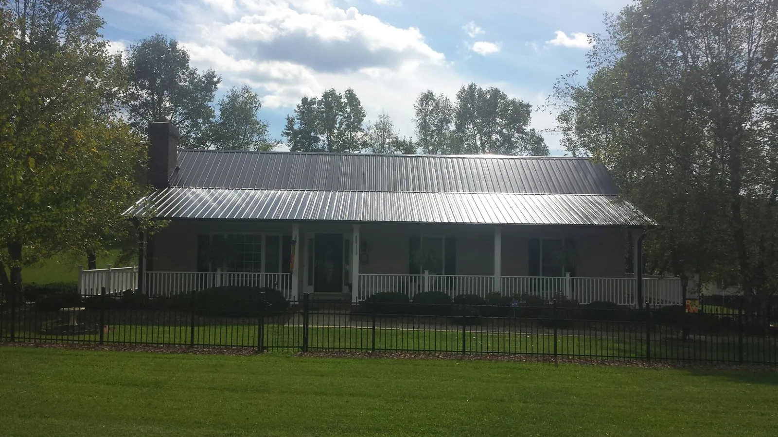 Gray metal roof on a brick ranch with a full width front porch — Gutter Guard Installation work by our crew in Esmont