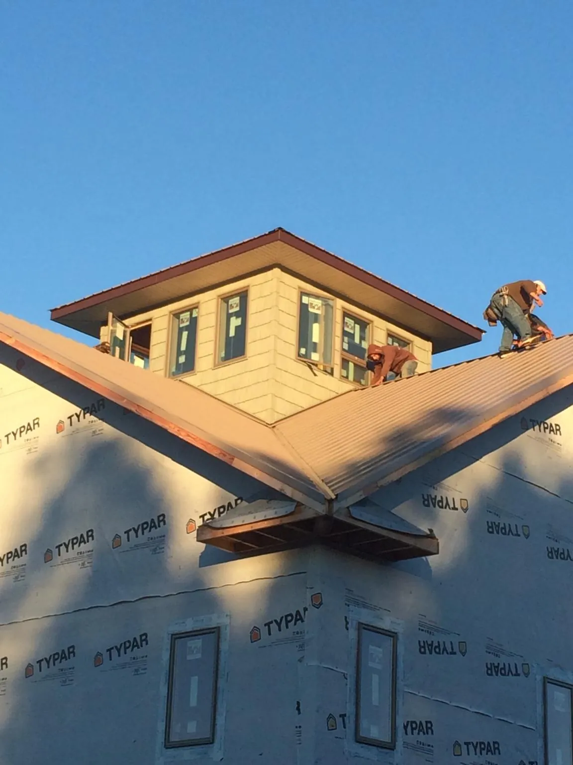 Roofers working around a rooftop cupola on a new metal roof at sunset — Roof Waterproofing in Esmont by Roofing Brothers